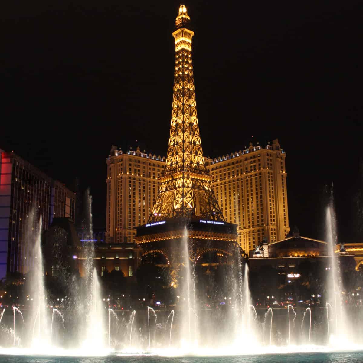 Bellaggio Fountains with the Paris Eiffel Tower lit up in the background 