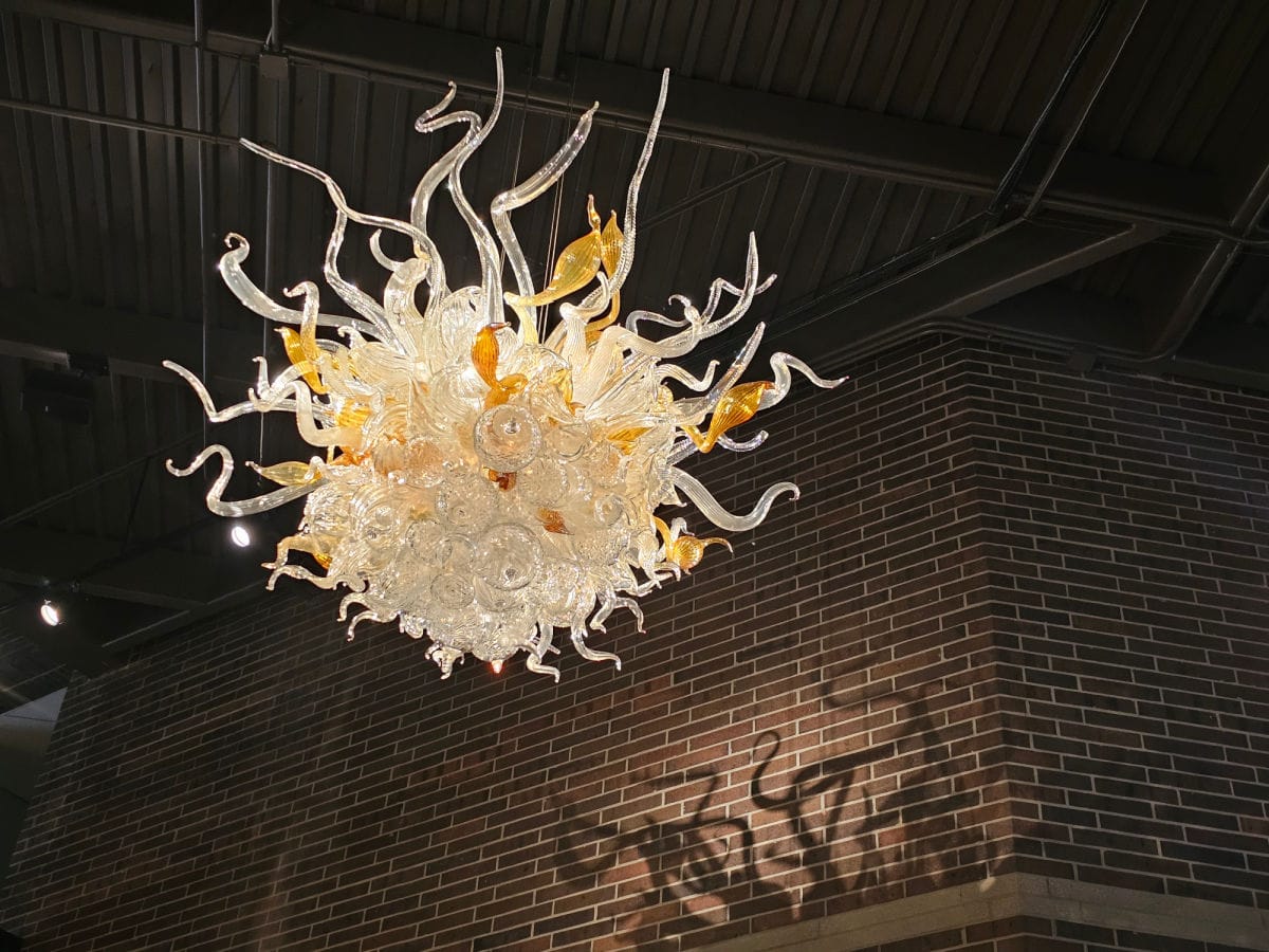 chihuly glass chandelier with reflection on the brick wall near it