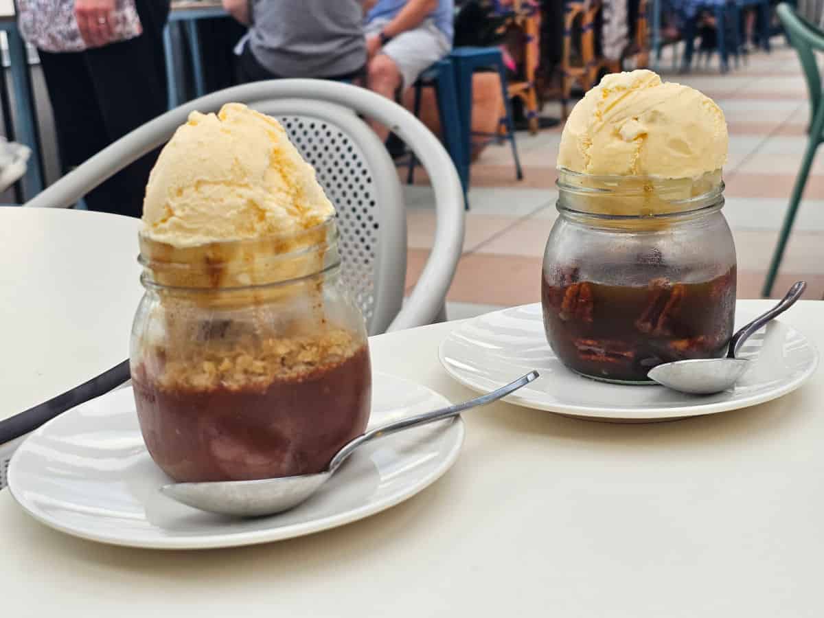 Cobblers in jars on white plates with scoops of vanilla ice cream on top