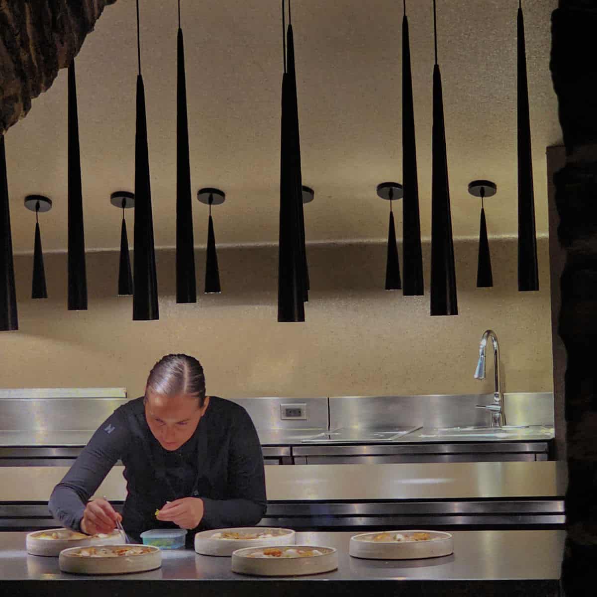 Chef with tweezers plating food in Restaurant Tanière3