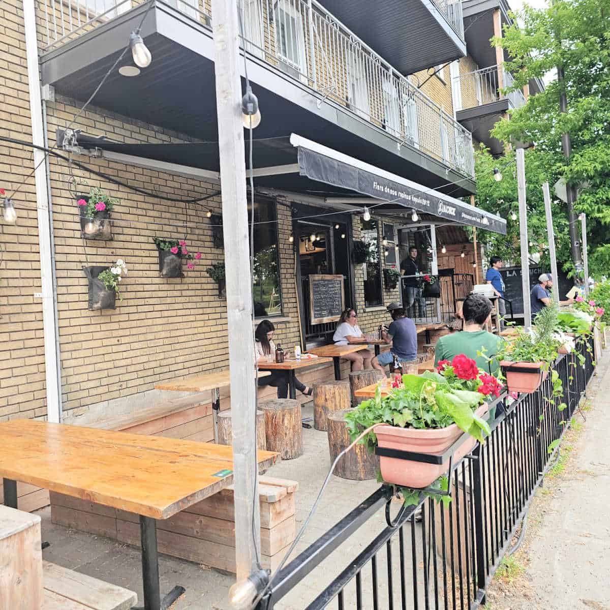 La Souche Limoilou exterior with tables and chairs, plants along the railing