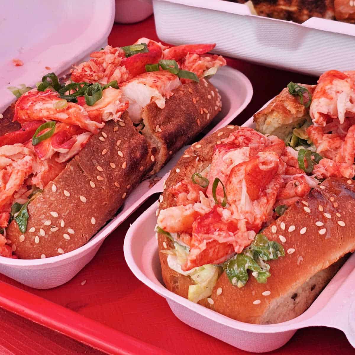 Lobster rolls in containers on a red tray