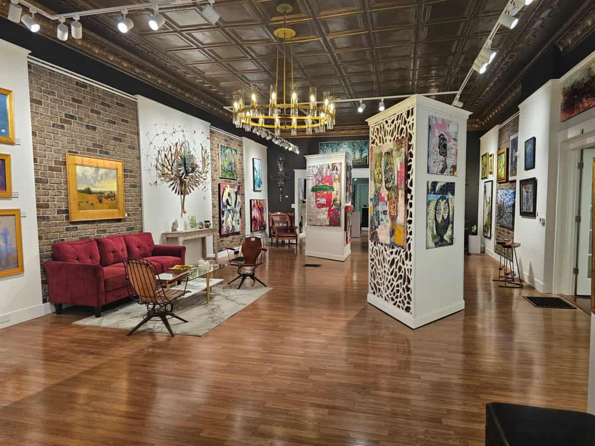 O2 Gallery with art on the wall, red couch and chairs,