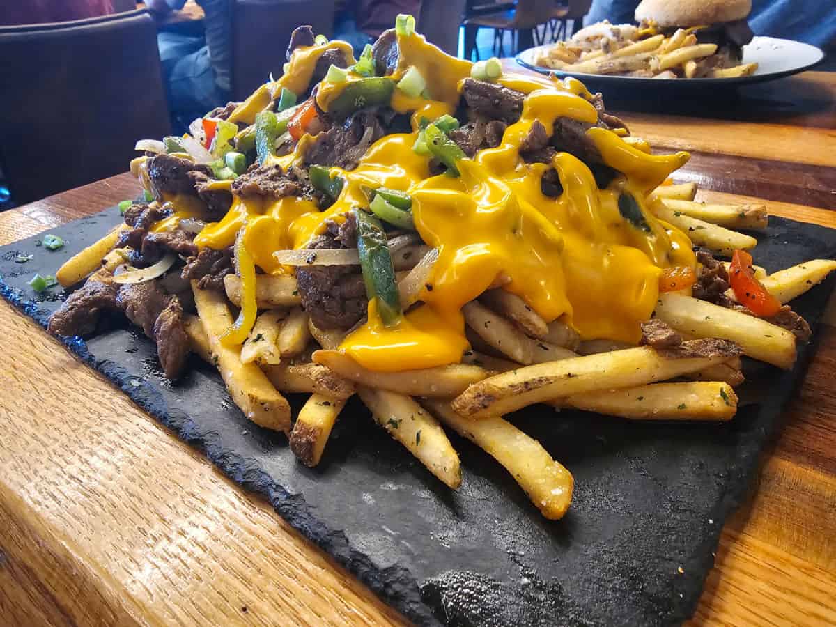 Philly cheesesteak fries on a slate platter on a table