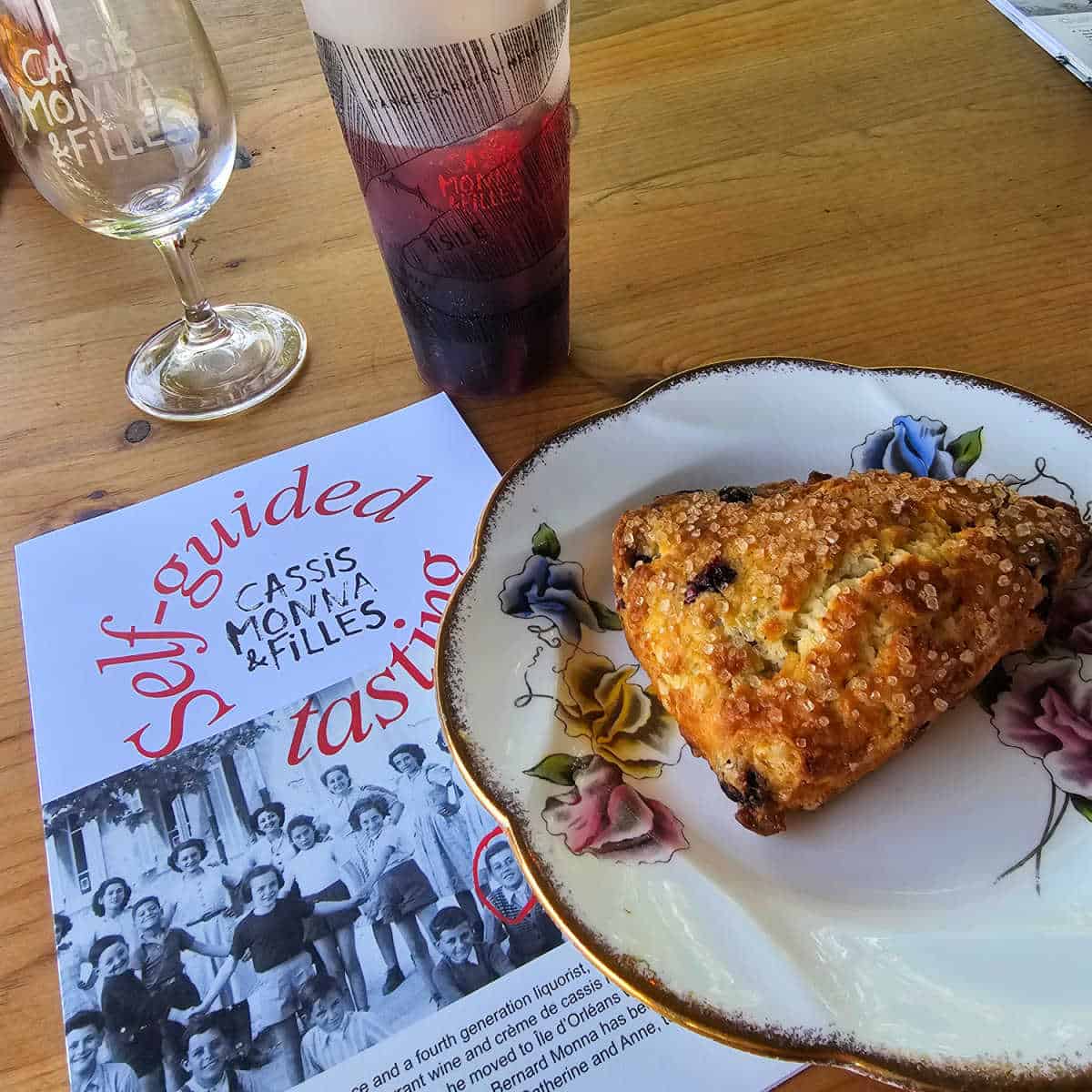 Cassis Monna & Filles self guided tasting sheet next to a plate with a blackcurrent scone, and glass of sangria
