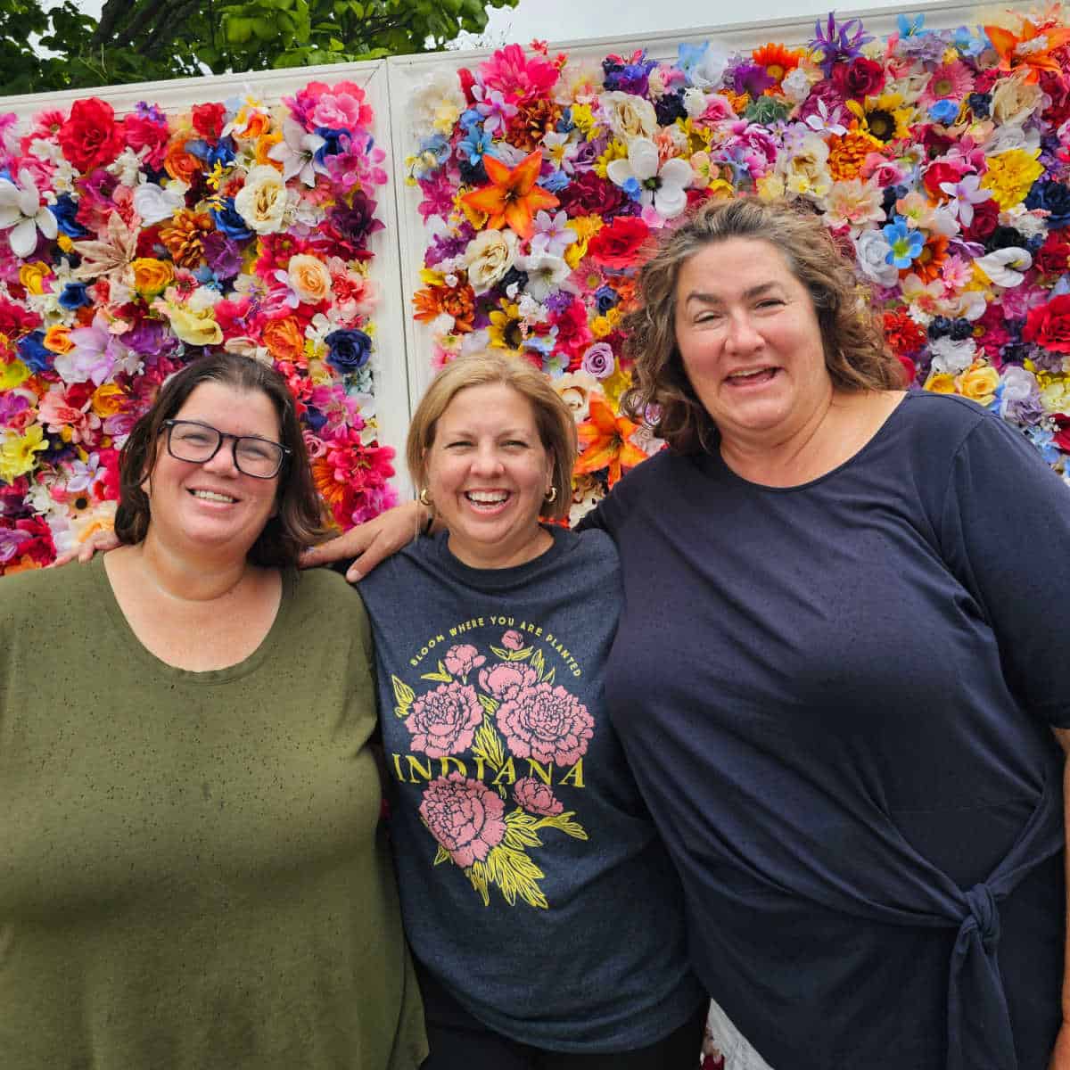 Tammilee, Kim, and kristen in front of a flower wall
