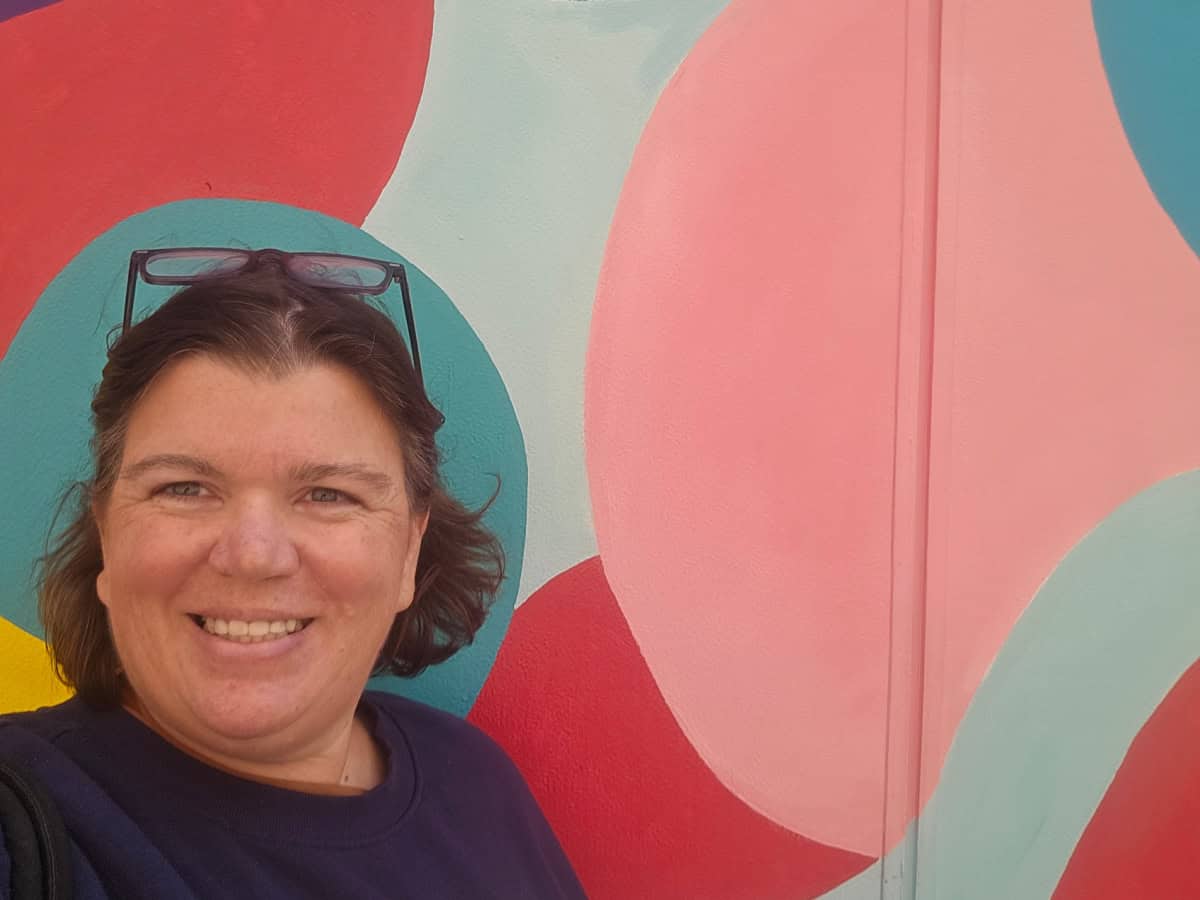 Tammilee next to a colorful mural