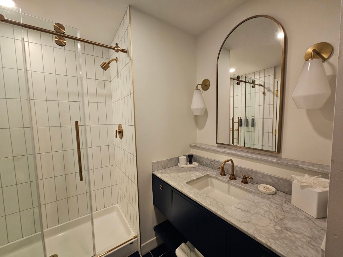 Bathroom with marble sink, mirror, and walk in shower