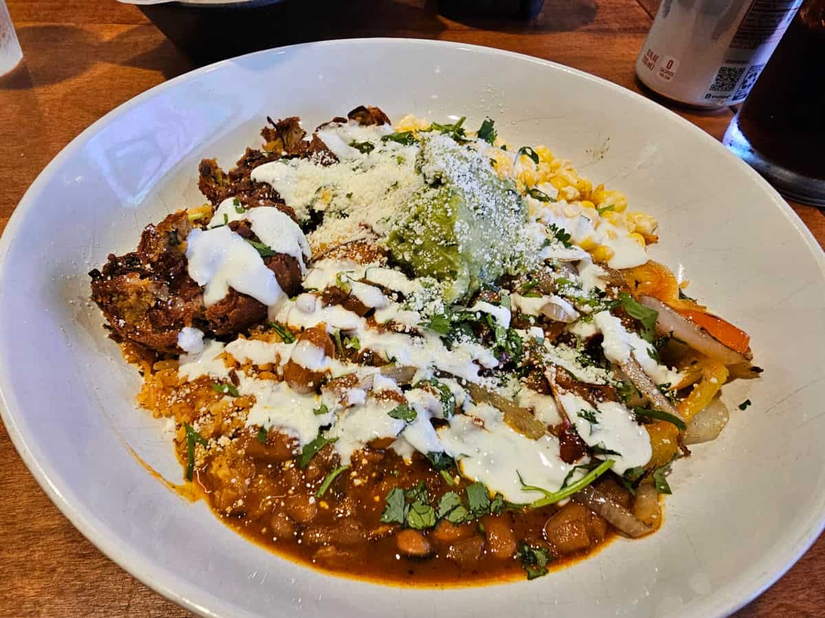 pinto bean falafel fajita bowl in a white bowl next to a drink