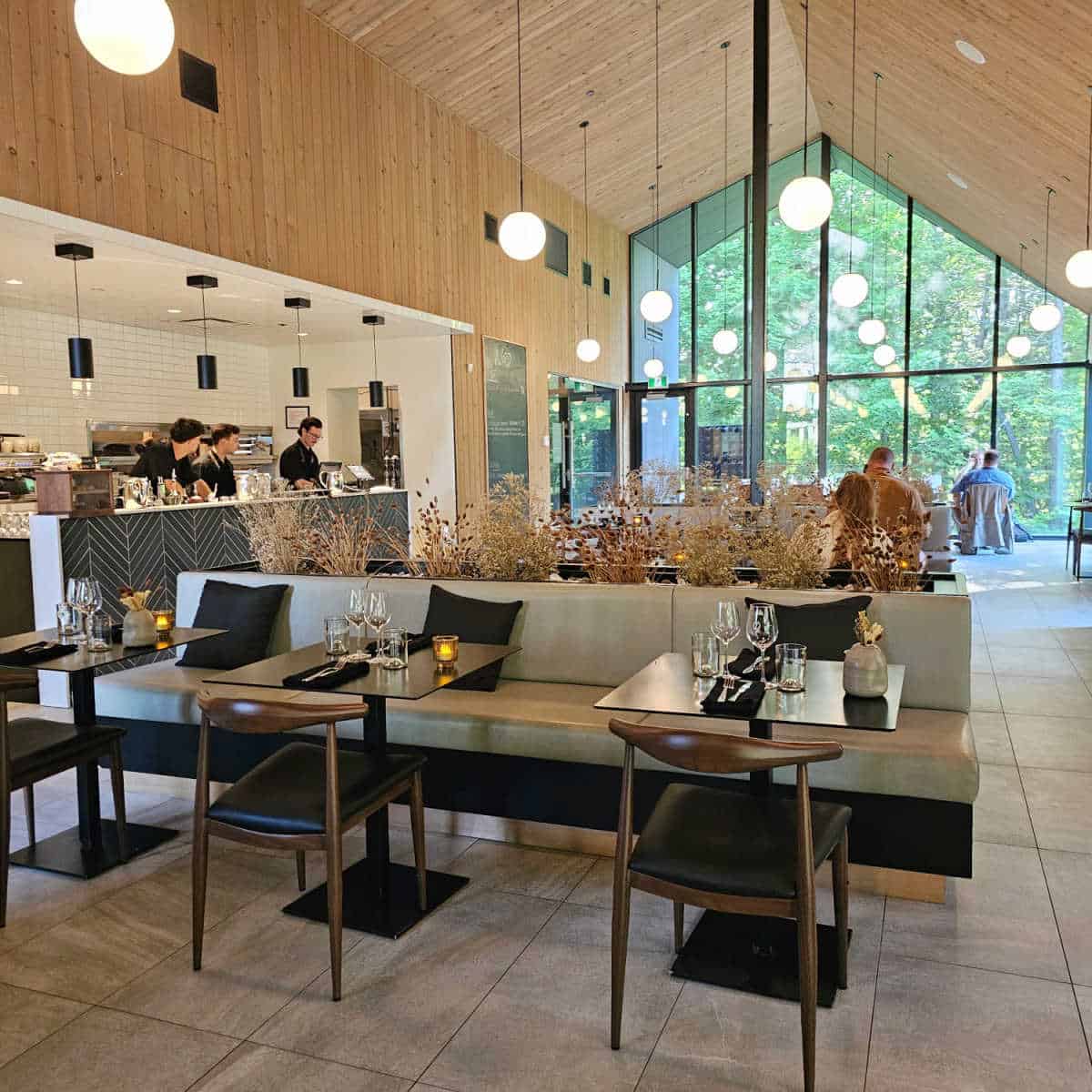 Bistro Nord at Strøm Spa dining area with tables and chairs, a large glass window and open views to the kitchen area