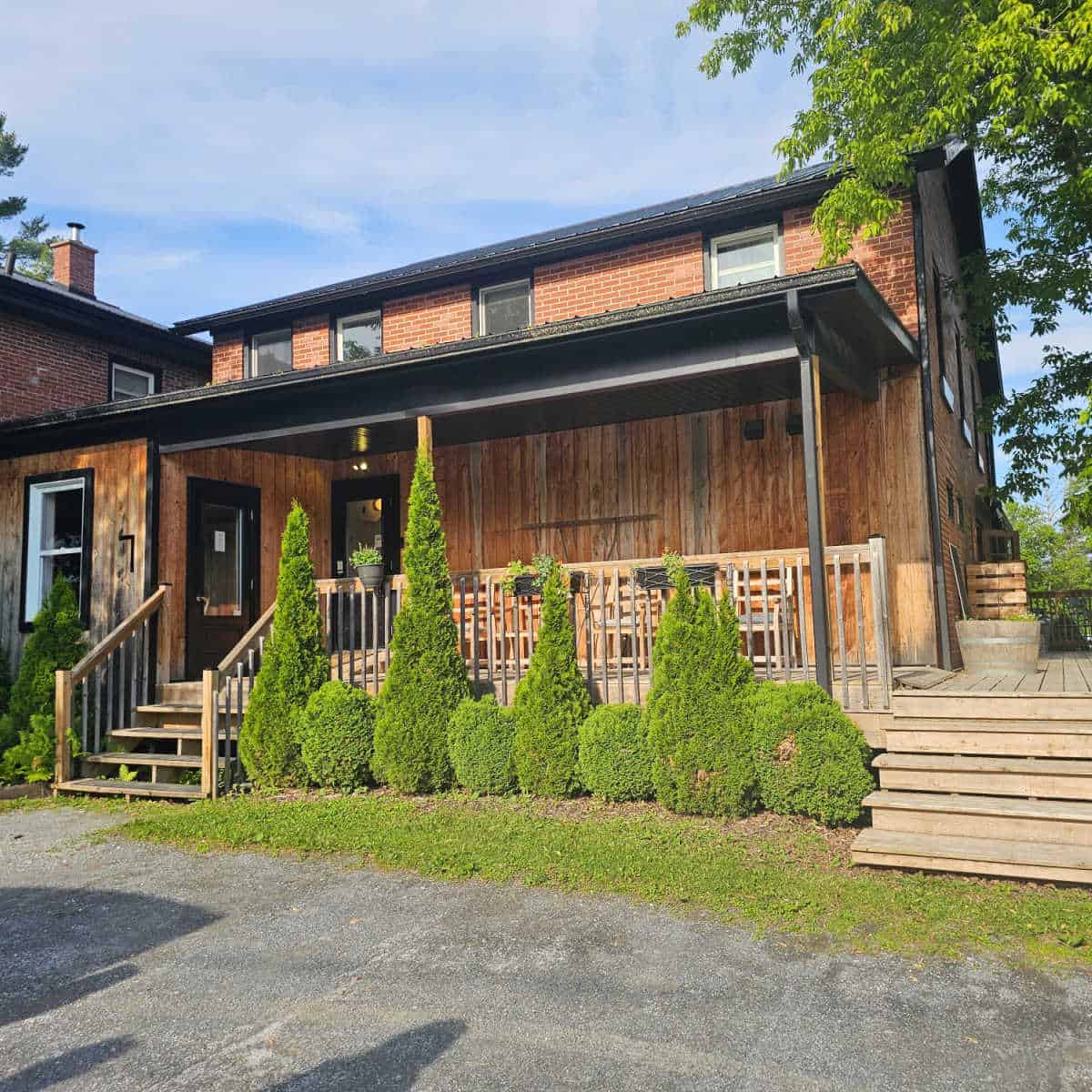 Wooden building exterior with green bushes and stairs leading up to a deck at Espace Old Mill