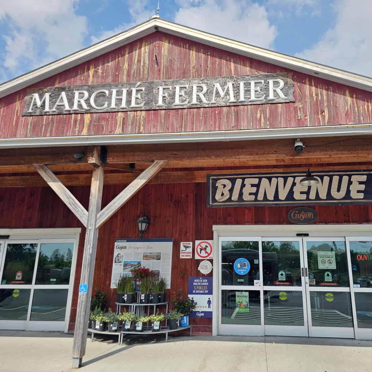 Marche Fermier sign on a red wood building with Bienvenue over the glass entrance doors