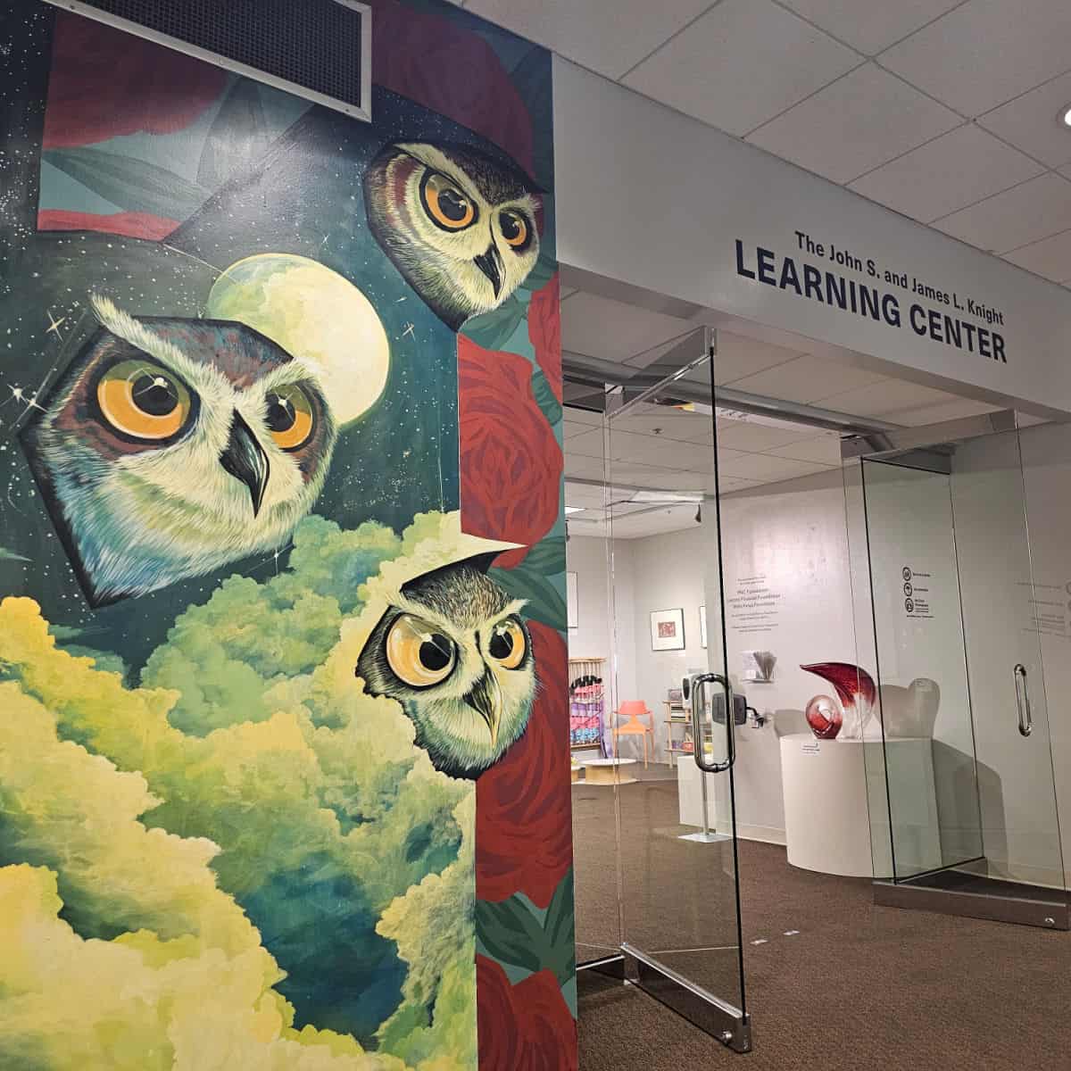 Owl mural with clouds and moon, next to a sign for the John S and James L Knight Learning Center