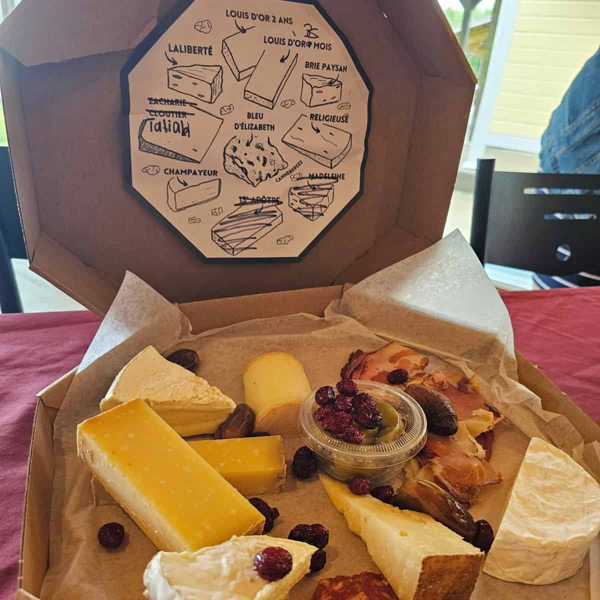 Box of Fromagerie du Presbytere cheese with craisins, prosciutto, and information on the cheese at the top of the box.