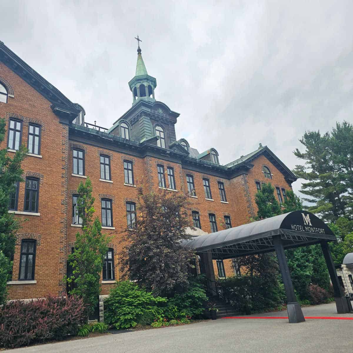 Hotel Montfort entrance with a covered walkway up to the stairs leading into the large brick building