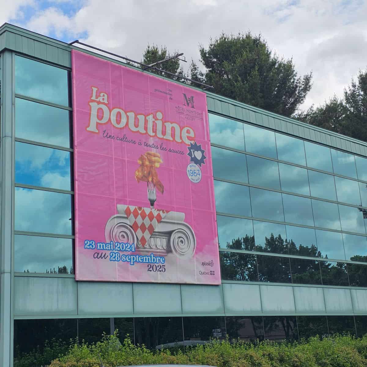 Pink sign on the side of a glass building with La Poutine