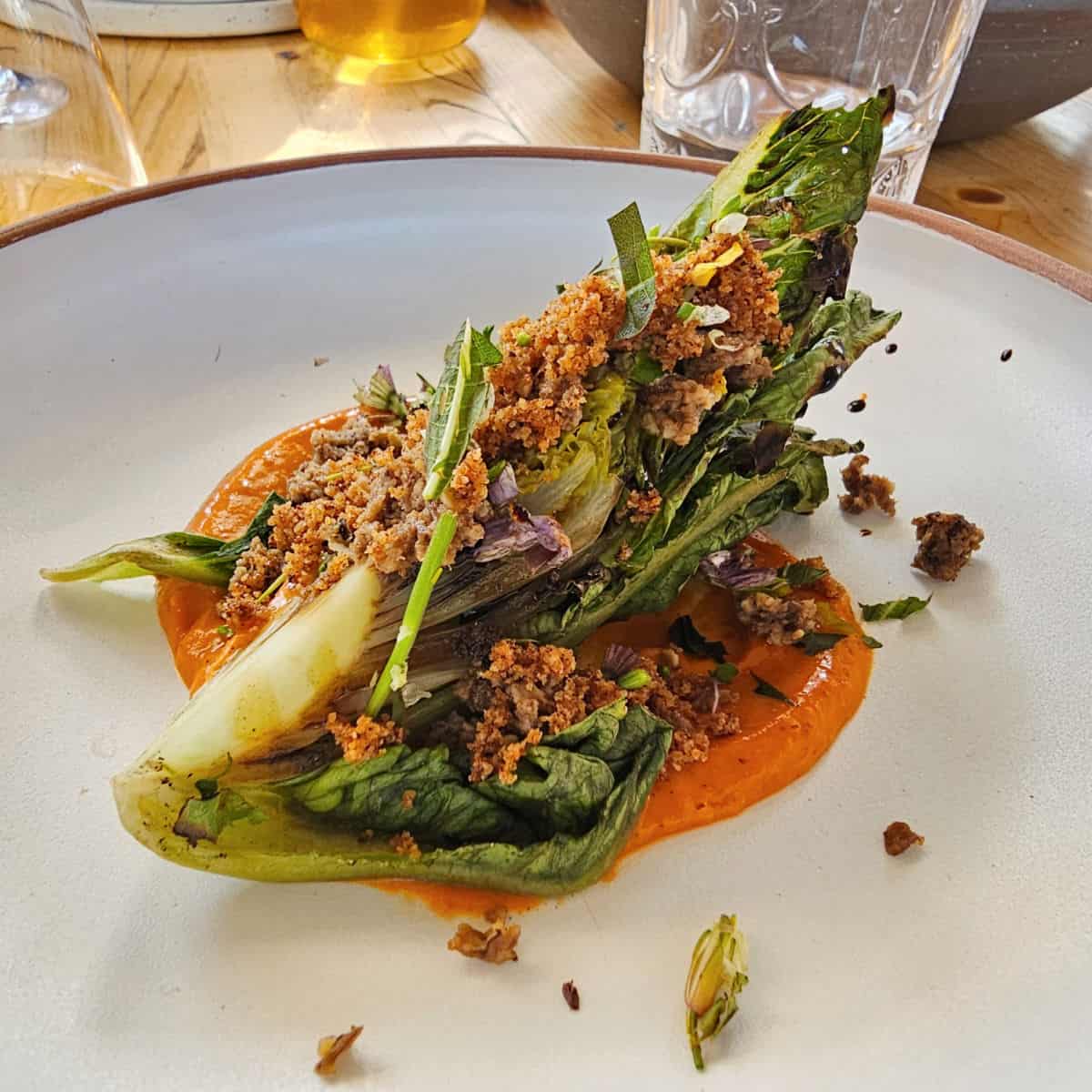 heirloom lettuce on a sauce on a white plate