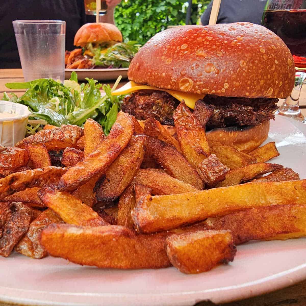 Veggie burger with fries and salad on a white plate at Brasserie Dunham