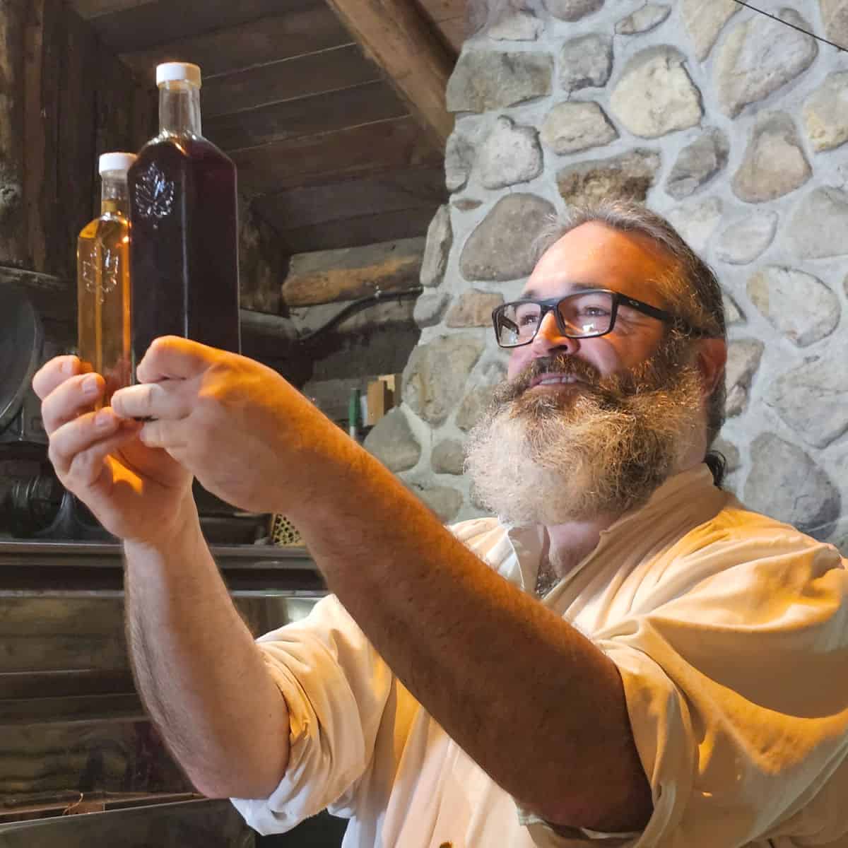 Stefan Faucher holding up two bottles of maple syrup