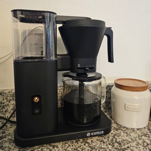 Kismile Coffee maker brewing next to a container with coffee on it
