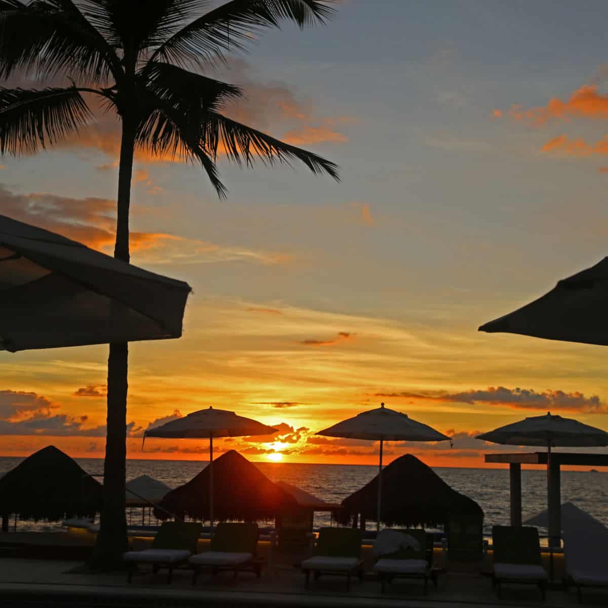 Sunset over the Bay of Banderas in Puerto Vallarta through beach umbrellas