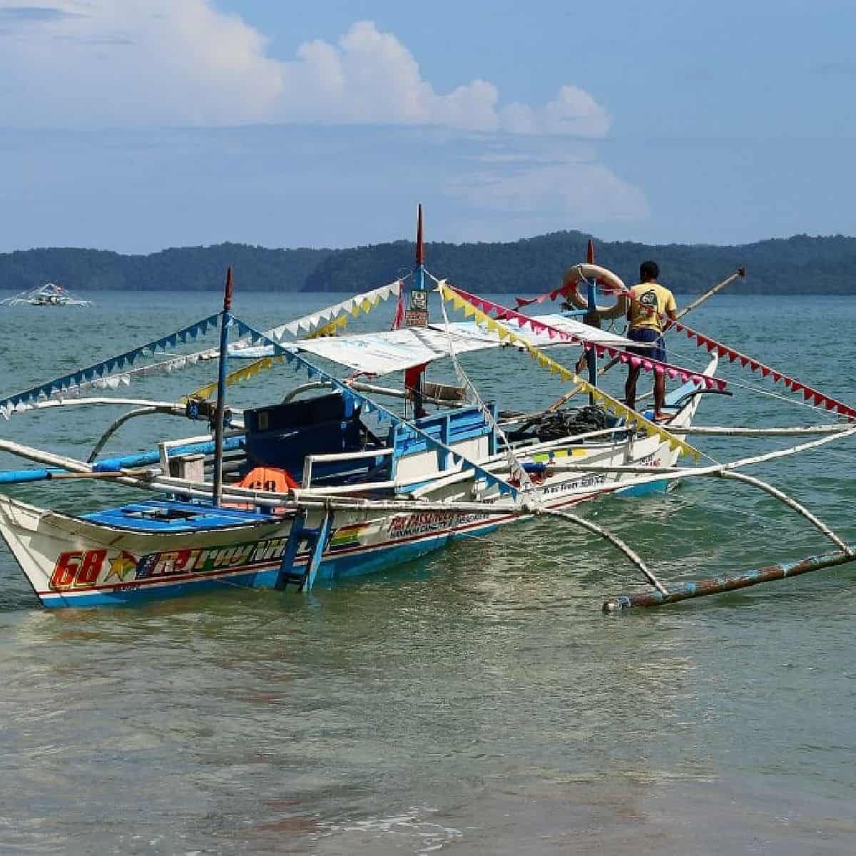 boat taxi with colorful flags and a boat captain with a pole at the back of it